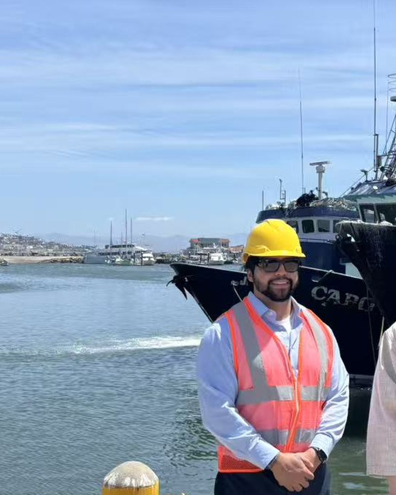 Jesse Regalado on the water, working gear, fishing fleet behind